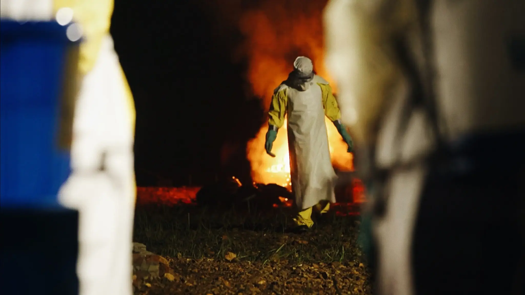 A figure tending a fire at night