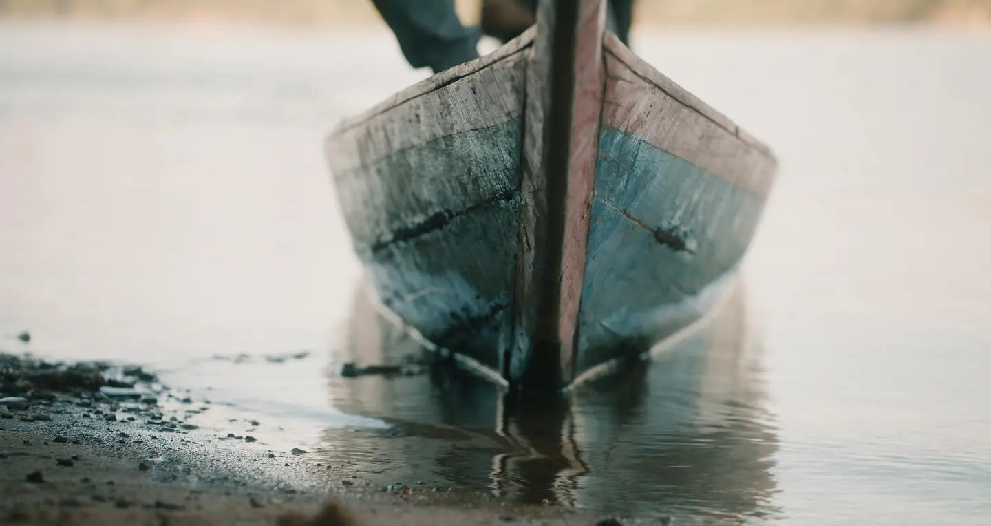 The bow of a weathered boat reflected in calm water